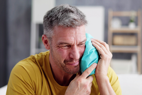 man with an ice pack on his jaw suffering from severe tooth pain in San Antonio