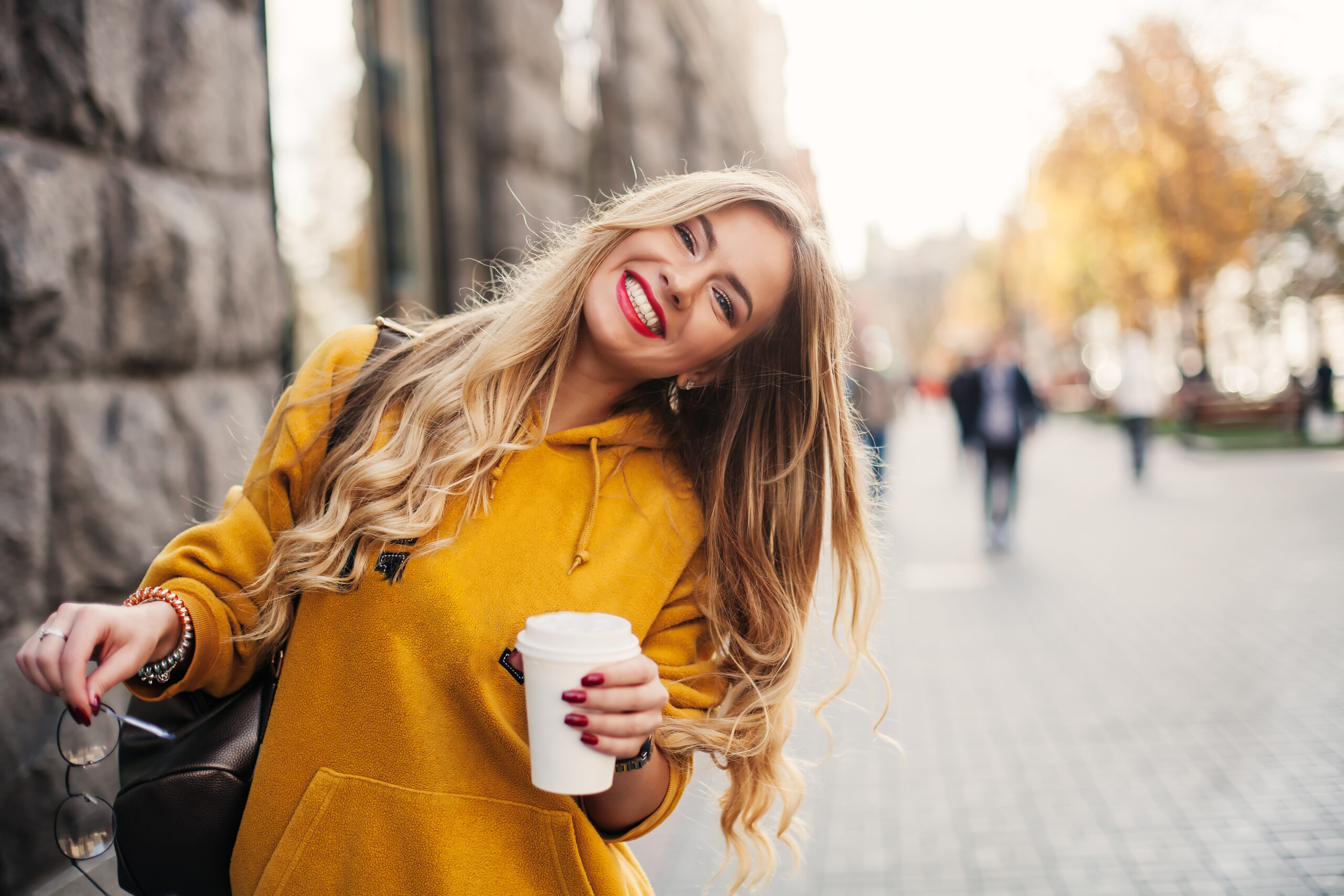 young woman in a yellow sweater smiling, showing off her new white smile
